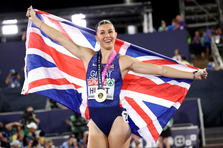 Gold medalist Amy Hunt of Team Great Britain smiling and holding up the Union Jack flag after winning the Women's 200 Metres Final.