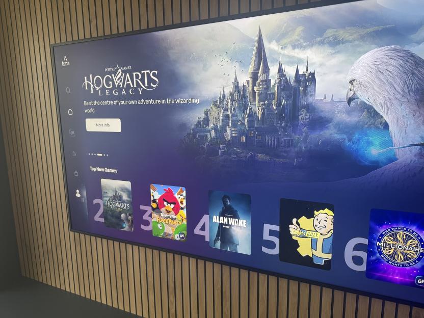 A TV displaying the Hogwarts Legacy game, with other game titles like Angry Birds and Alan Wake underneath.