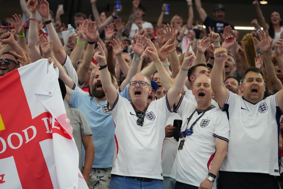 Fans cheering and holding an England flag during a FIFA World Cup 2026 match.