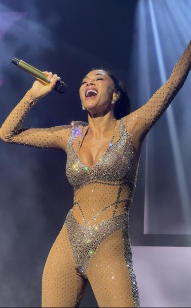 Nicole Scherzinger performing on stage in a shimmering, nude-colored bodysuit.