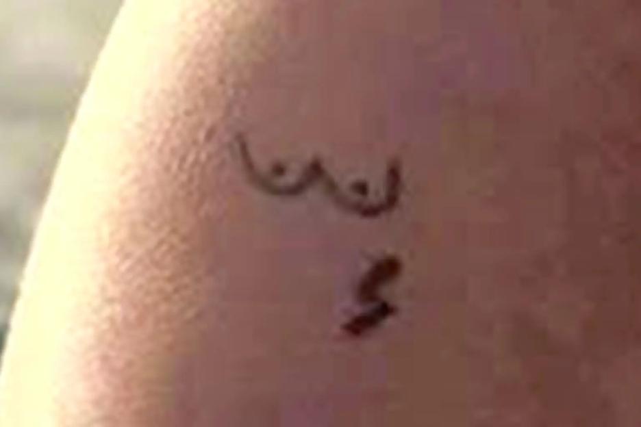Temporary tattoo of breasts and a small figure below on skin.