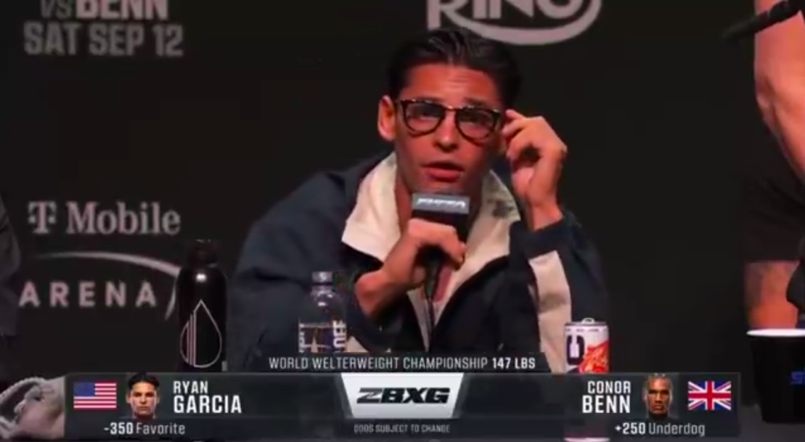 Ryan Garcia speaking at a press conference, with fight details for a World Welterweight Championship against Conor Benn shown below.