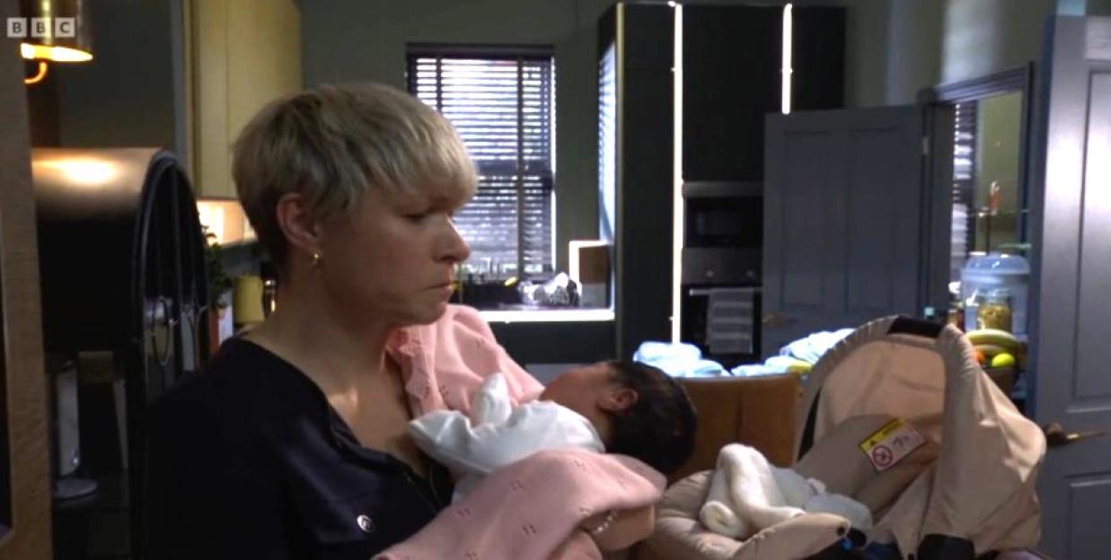 A woman with short blonde hair cradling a baby.