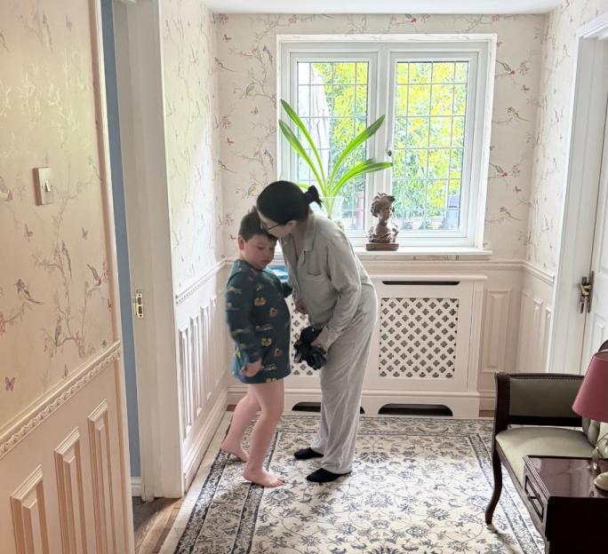 A mother leaning down to kiss her neurodivergent son, Sid, on the forehead.
