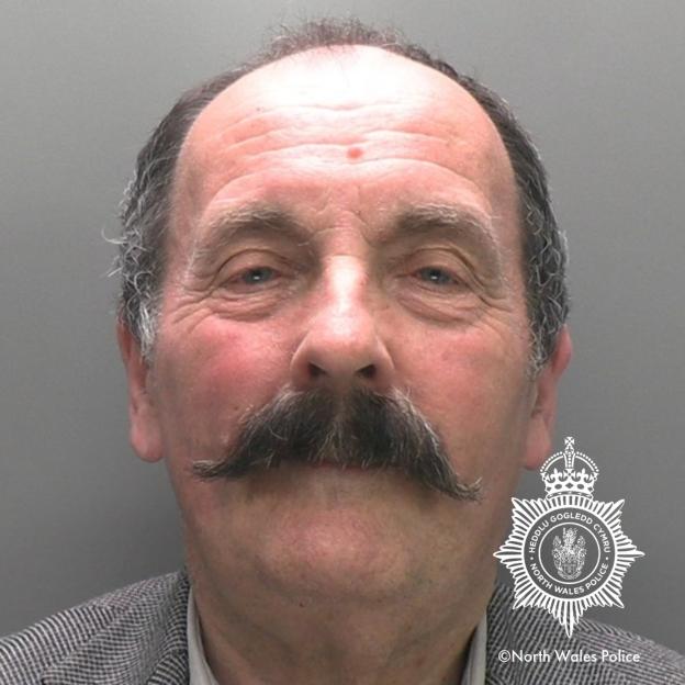 Mugshot of John Starkey, a 74-year-old white man with a large dark mustache, wearing a patterned jacket.