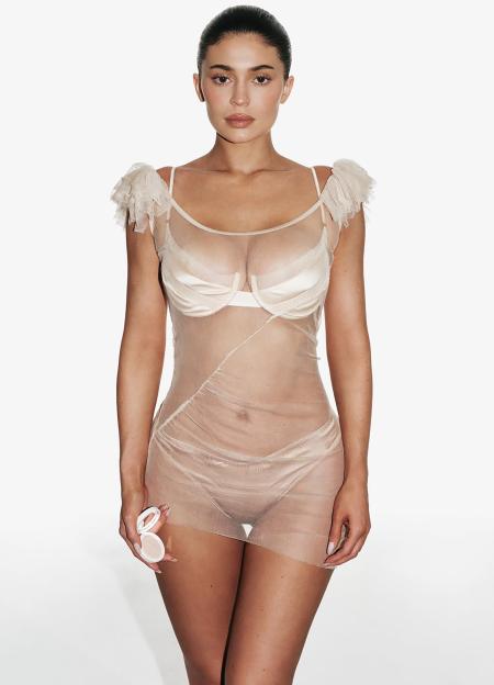 Kylie Jenner in a sheer mesh dress, holding Kylie Cosmetics' Natural Blur Brightening Powder.