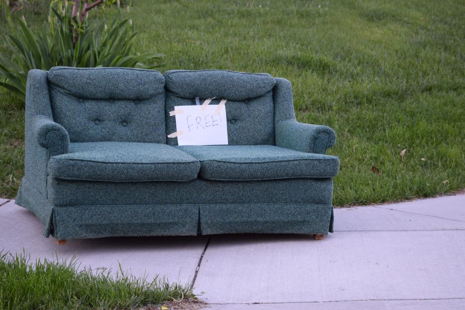 A green sofa with a "FREE!" sign on a sidewalk.