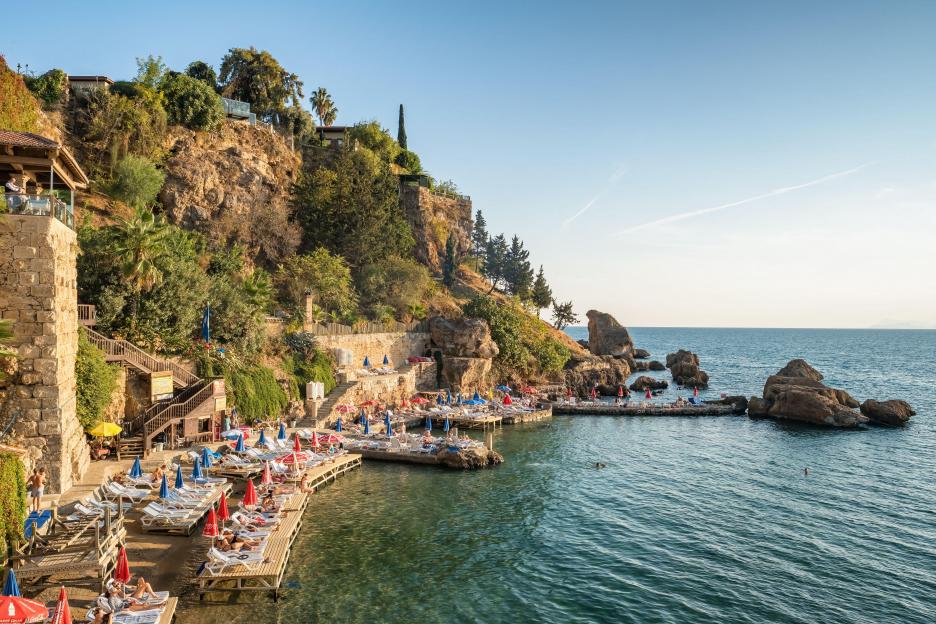 Unidentified people sunbathing on the small beach in Kaleici old town of Antalya.