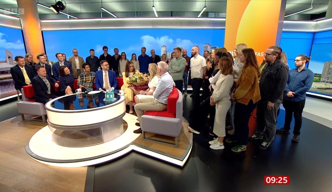 A group of people sitting on a talk show set with an audience behind them.