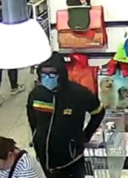 CCTV image of a person in a black hoodie and blue face mask.