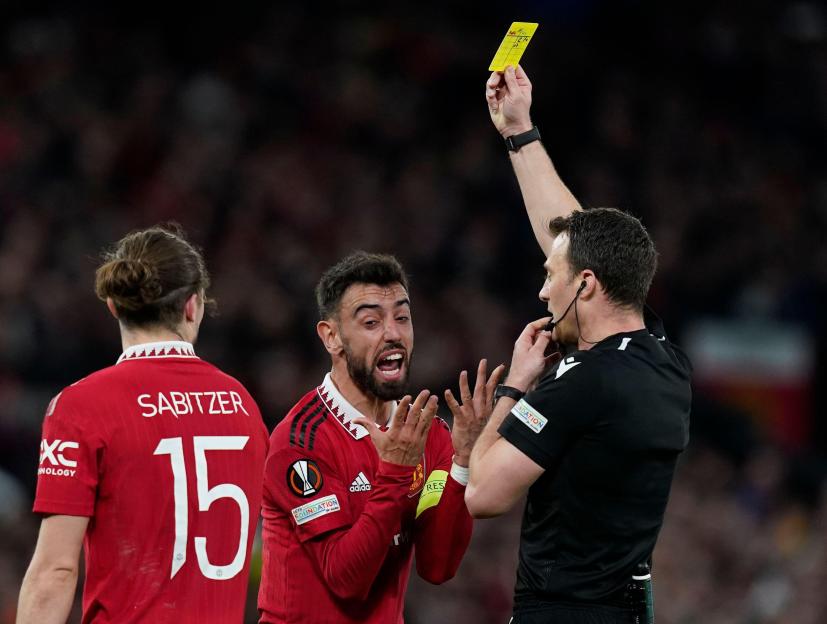 Referee shows a yellow card to Manchester United player Bruno Fernandes.