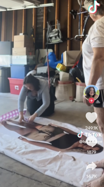 A person prepares a life-sized cardboard cutout of a person in a garage.