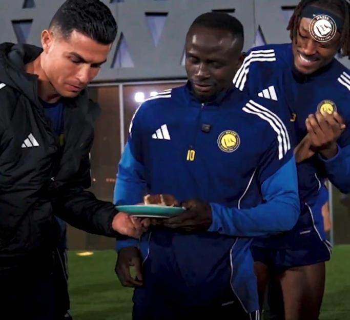Cristiano Ronaldo, Sadio Mané, and another teammate celebrate with a cake.