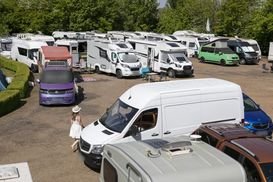 A person walking past a large gathering of RVs and campers at the Swingathon May Weekender.