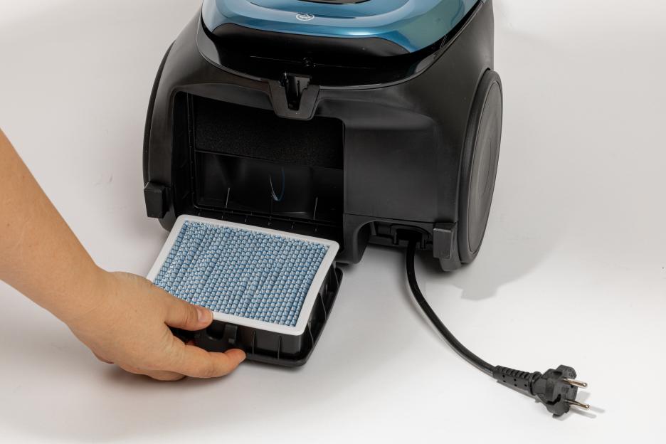 Hand Removing HEPA Filter From Canister Vacuum Cleaner During Home Cleaning Maintenance
