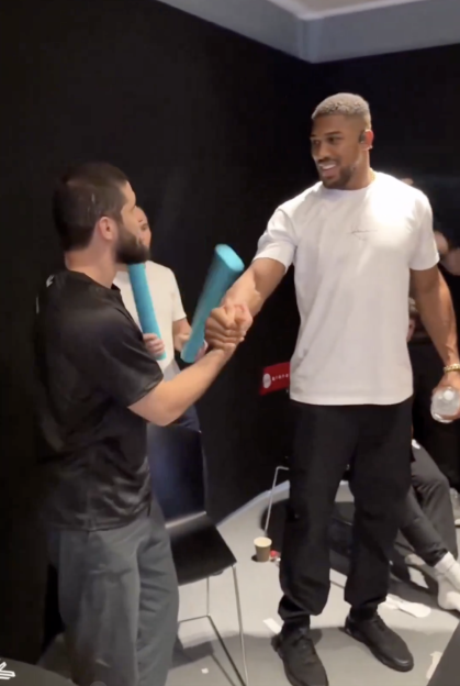 Anthony Joshua shaking hands with a man holding a blue foam roller.