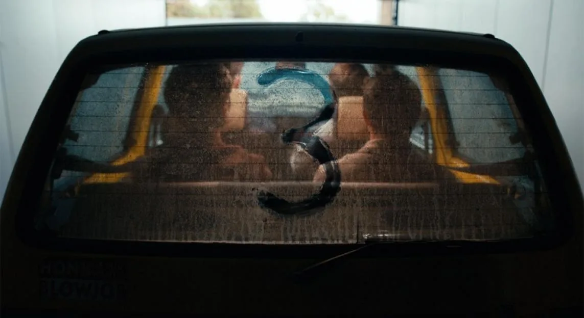 The back window of a car with a number 3 written on the fogged-up glass.