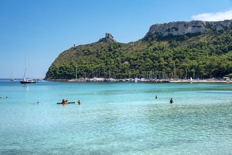 Poetto beach, crystal clear water and the famous Sella del Diavolo, Cagliari, Sardinia, Italy