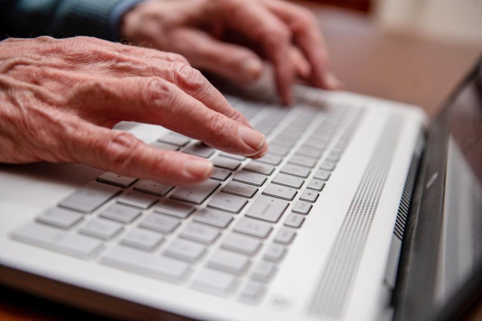A person's hands typing on a laptop keyboard.