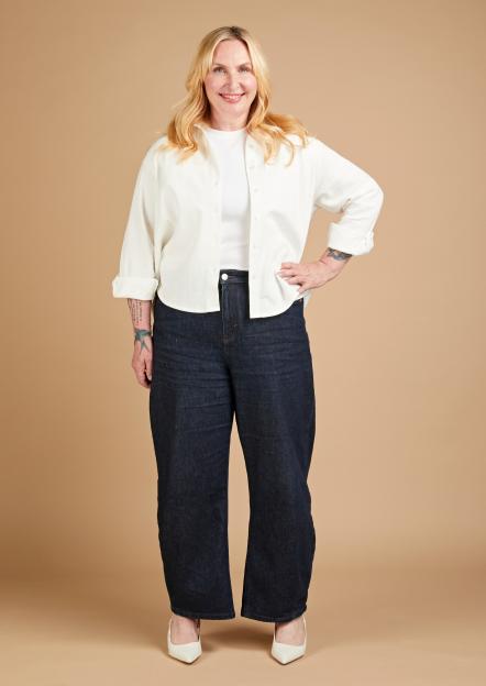 Annikki Sommerville wearing wide-leg jeans, a white t-shirt, and an open white button-up shirt, with white heels.