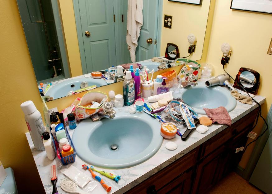 A cluttered bathroom vanity with two light blue sinks filled with health and beauty products.