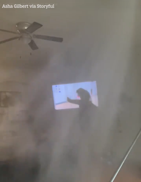 A room filling with water from a sprinkler, with a woman practicing pole dancing reflected on a screen.