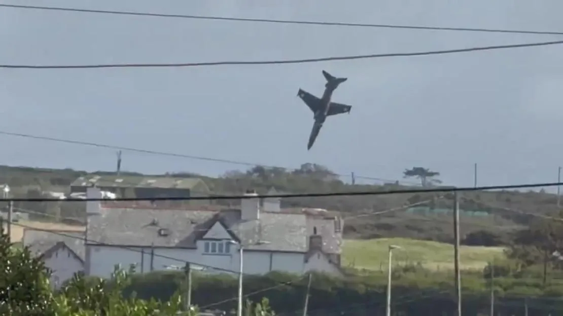 A Hawk T2 training aircraft falling steeply from the sky near a village.