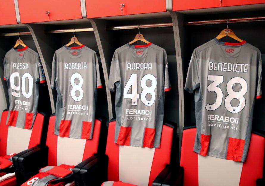 Football jerseys of players Alessa (90), Roberta (8), Aurora (48), and Benedicte (38) hanging in lockers.