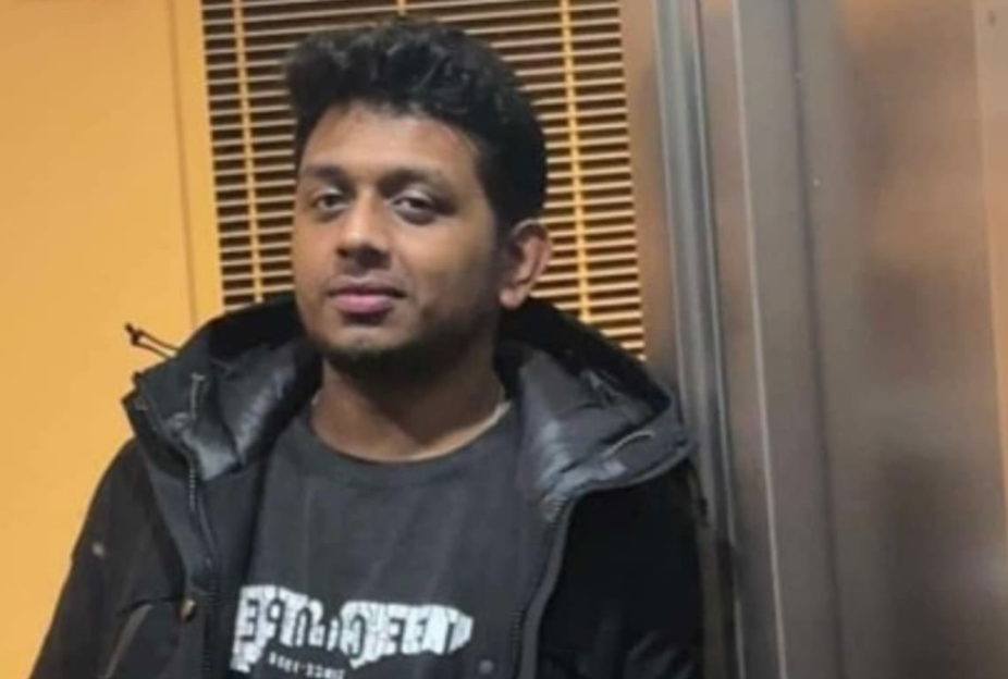 A young man in a black jacket and T-shirt.