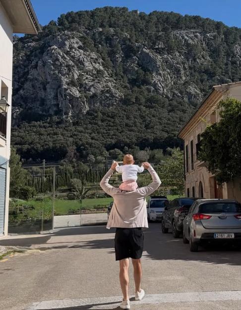 Man carrying a baby on his shoulders while walking on a street in Mallorca.