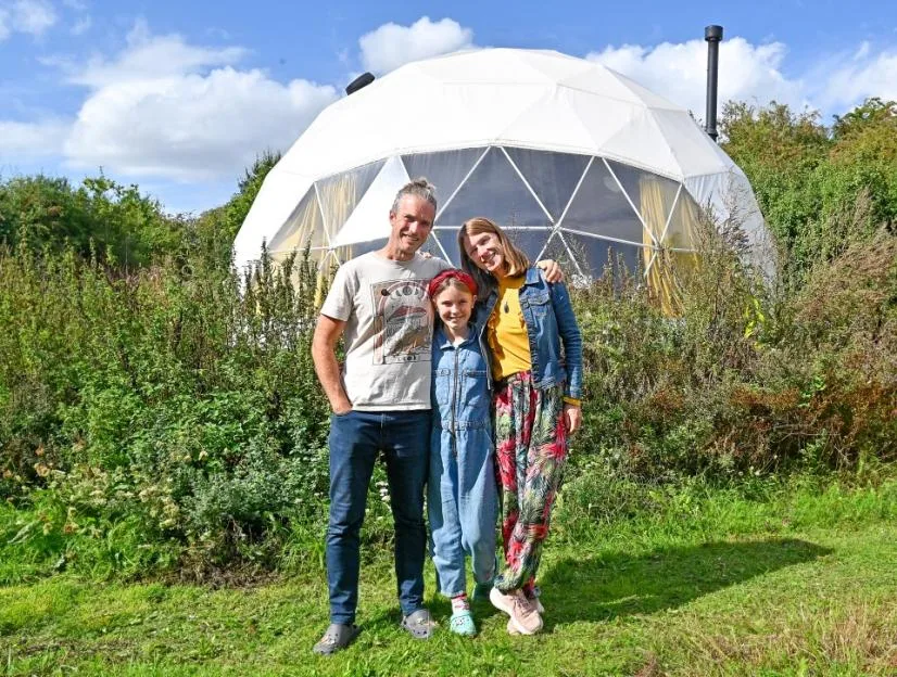 Holly and Jon Wright with their daughter outside their off-grid geodesic dome home at Jolly Moon in South Wonston.
