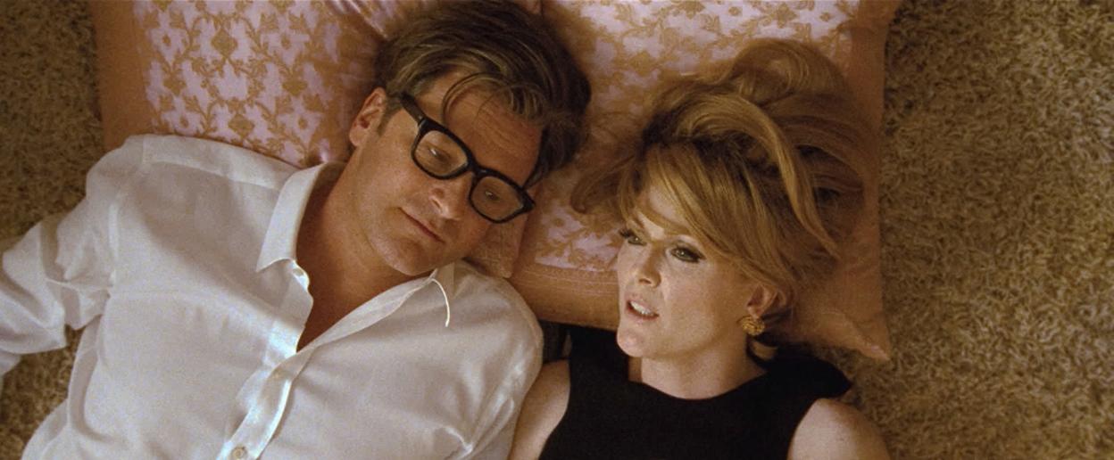A film still from A Single Man shows two actors, a man in glasses and a woman, lying on the floor.