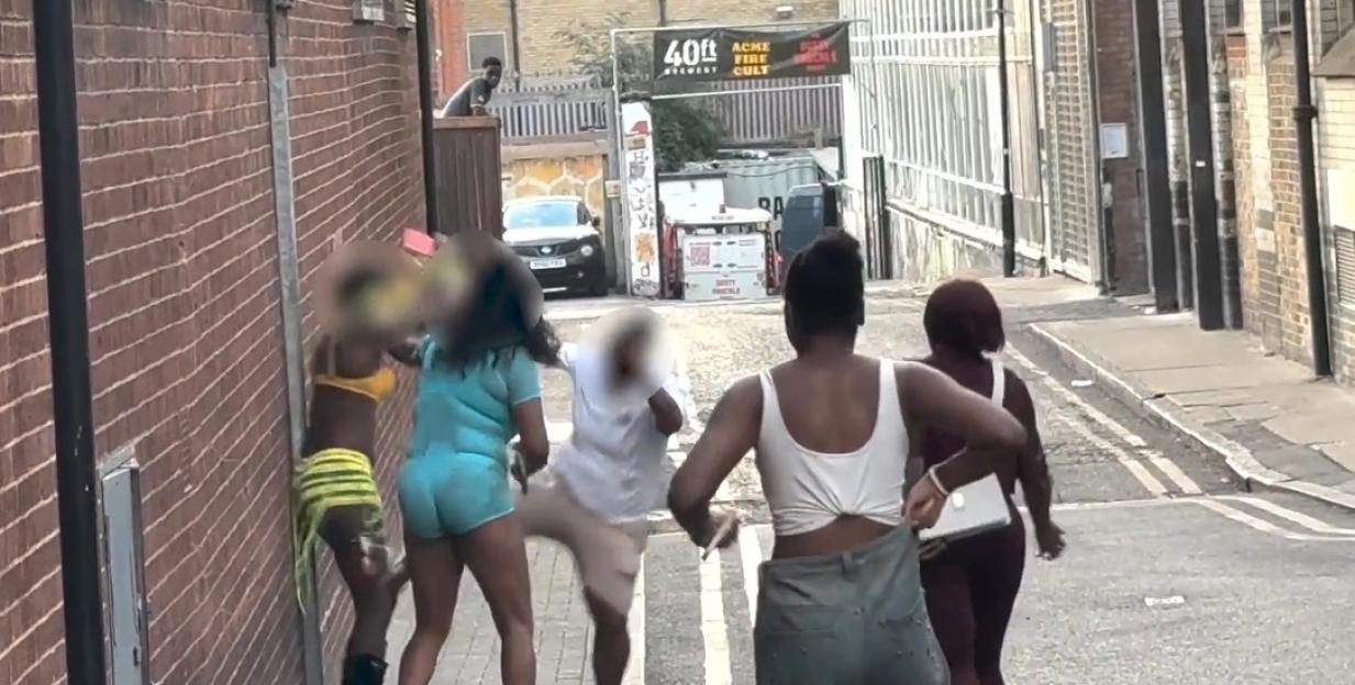Five women fighting in a street alley.
