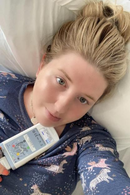 A woman in a hospital bed holding a medical device.