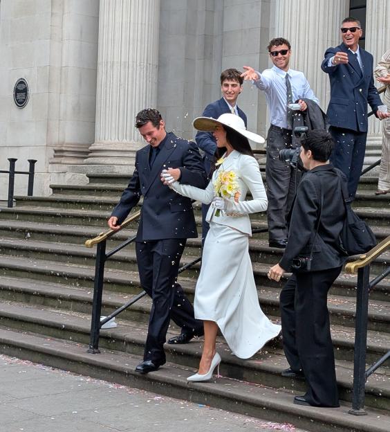 Dua Lipa and Callum Turner leaving their London wedding as confetti falls around them.