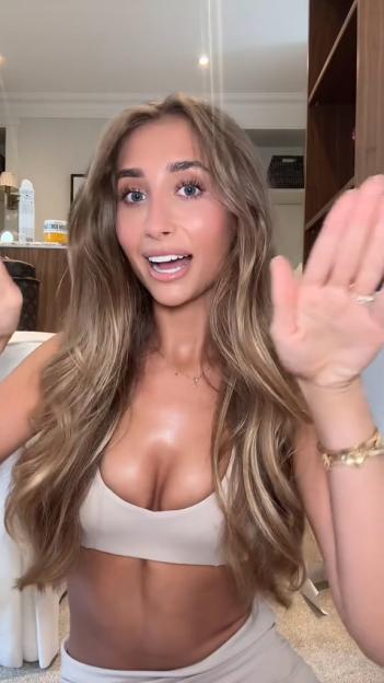 Lily Phillips wearing a sports bra, waving to the camera.