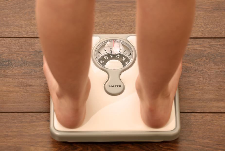 Person weighing themselves on a scale.