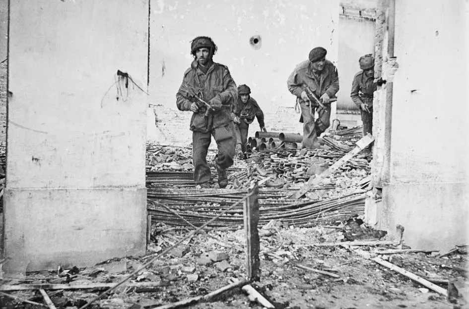 Four British paratroopers moving through a shell-damaged house in Oosterbeek.