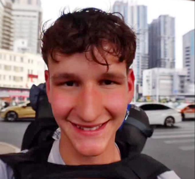 Tommy Lamb, a super-fan known as Cheese Naan, smiling at the camera with a city street in the background.