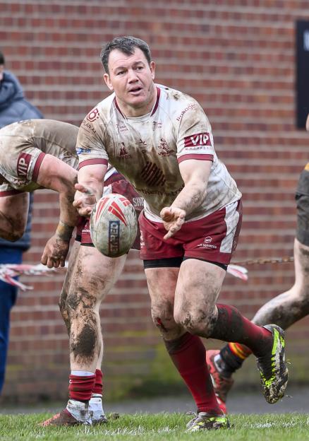 Brett Ferres, muddy and in uniform, passes a rugby ball.