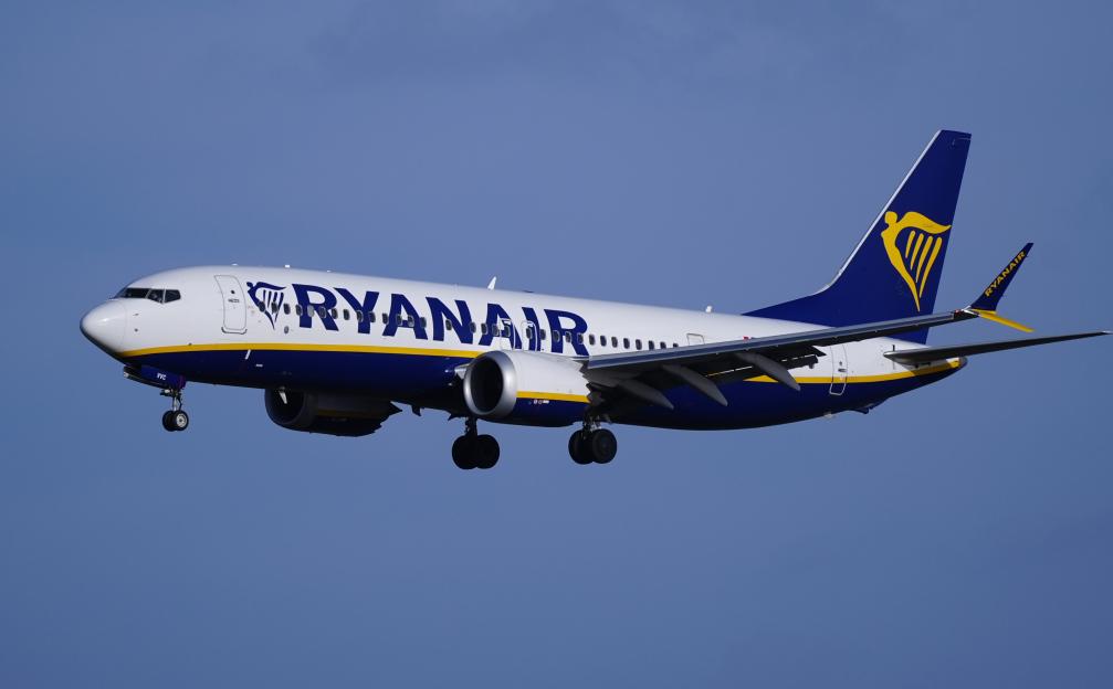 A Ryanair airplane flying against a clear blue sky.