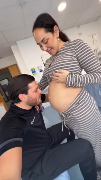 Jordan Brook kissing his partner's pregnant belly.