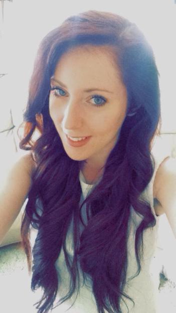 Sarah Barnett, a woman with long wavy dark hair and blue eyes, smiles at the camera.