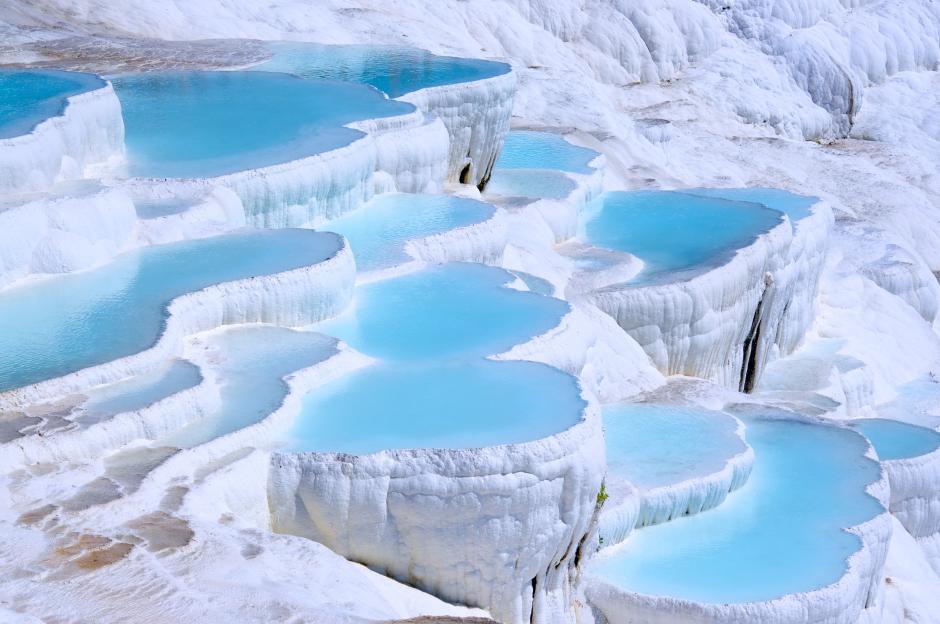 Pamukkale's white travertine terraces filled with bright blue mineral water.