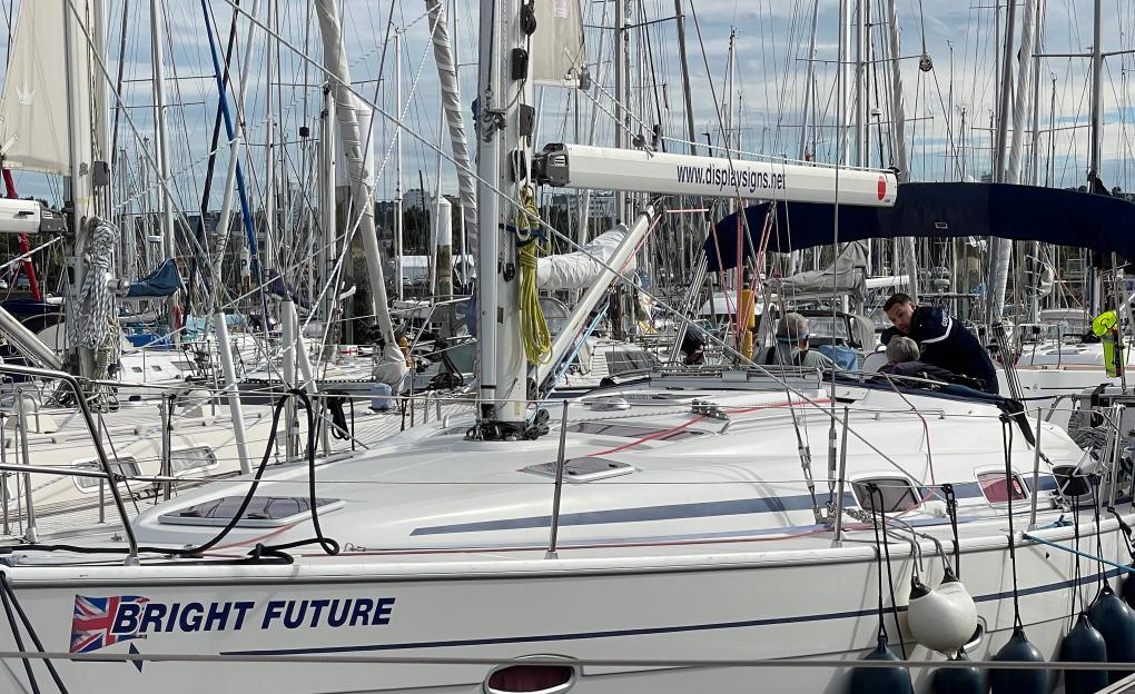 A French Gendarme speaks to a retired couple on their yacht named "Bright Future" docked in a marina.