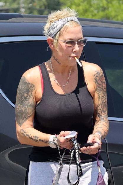 Kim Mathers smoking a cigarette while wearing a black tank top and bandana.