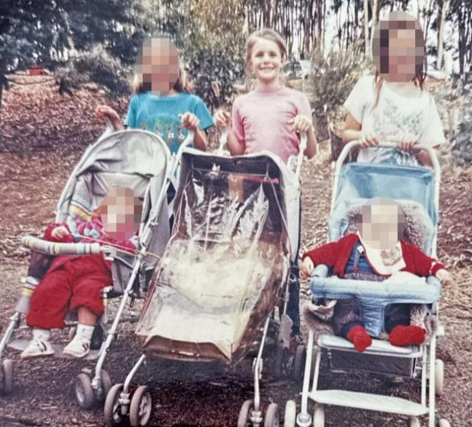 Three young girls pushing strollers with babies in them.