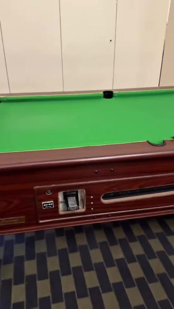 A green pool table with a coin slot.