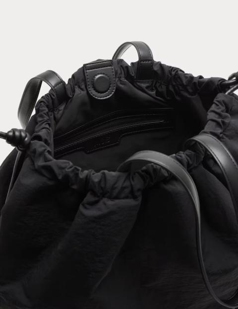 An open black drawstring shoulder bag with a black leather handle and black button snap closure.