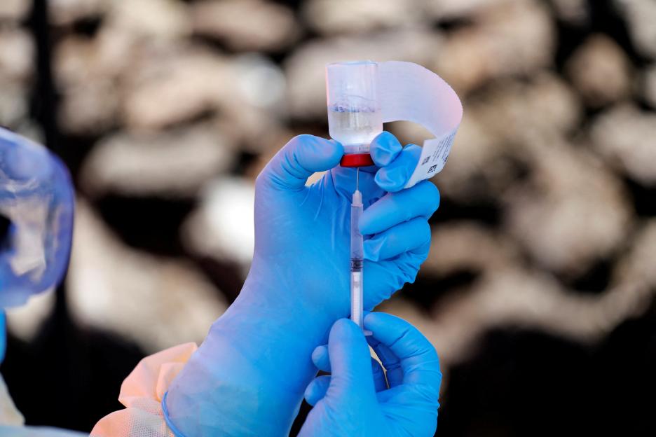 Health worker holding Ebola vaccine vial.